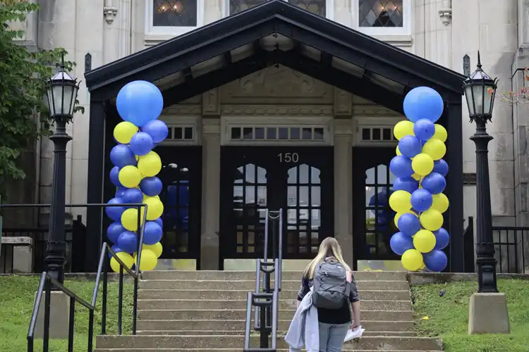 photo of library with balloons out front and a student walking in
