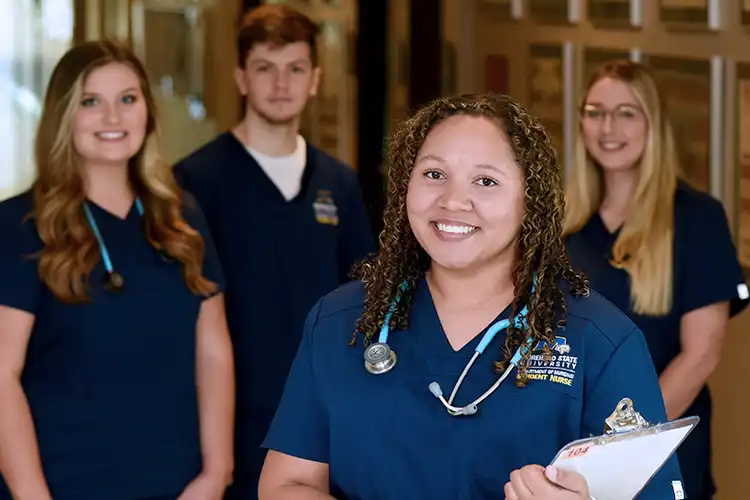 Several nursing students stand together in uniform.
