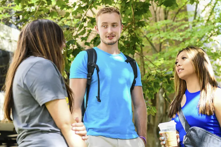 three students talking and laughing outside on campus
