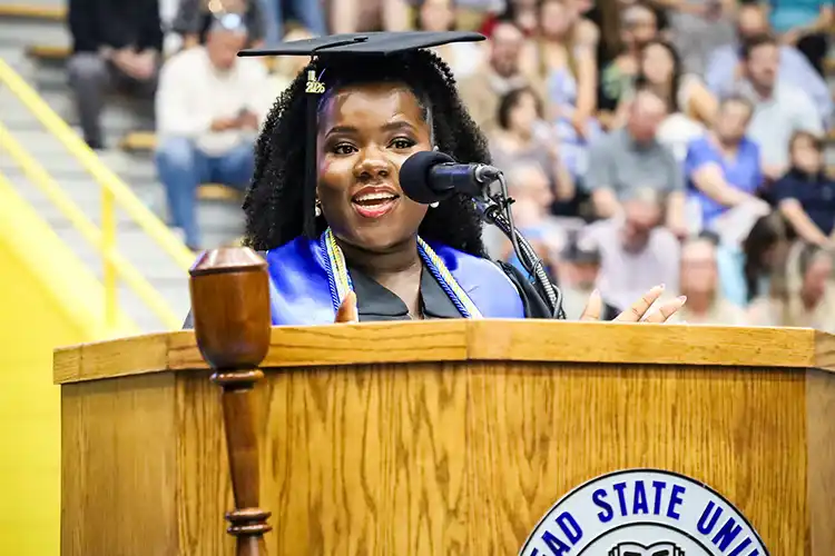 Marcella Muadi Batubenga speaking at podium at Spring 2026 Commencement.
