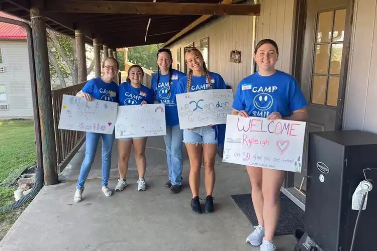 Emma Moudy and other MSU Nursing Students holding signs at Camp SMILE.