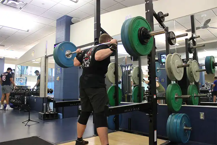 Recreation and Wellness Center Squat Rack With Student Squatting.
